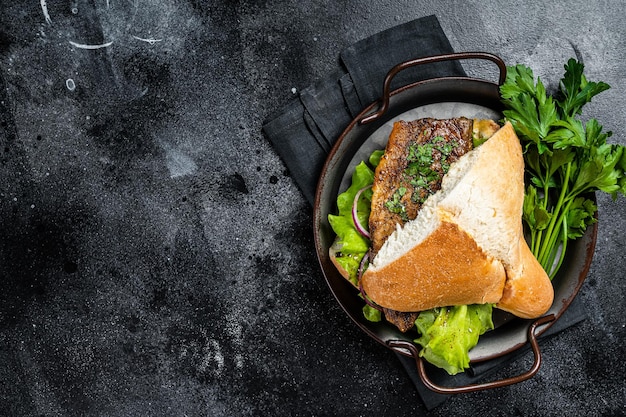 Sandwich balik Ekmek avec filet de poisson maquereau grillé tomates oignons et laitue Fond noir Vue de dessus Espace de copie