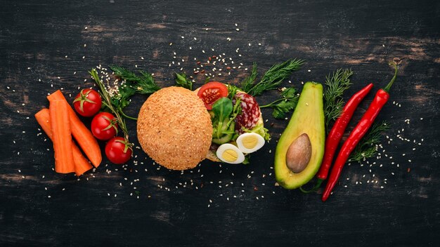 Sandwich burger avec des œufs de caille au salami et des tomates cerises Sur un fond en bois Vue de dessus Espace de copie