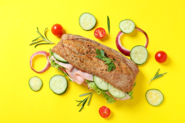 Sandwich ciabatta et ingrédients sur fond jaune