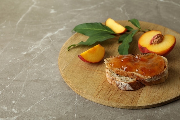 Sandwich avec confiture de pêches et ingrédients sur table texturée grise