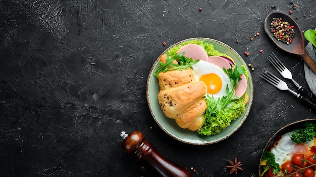 Sandwich croissant avec oeuf au plat et tomates saucisses et oignons Vue de dessus Espace libre pour votre texte