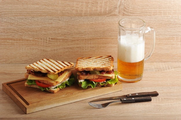 Photo sandwich à deux étages avec bacon et poitrine de poulet sur une planche de bois