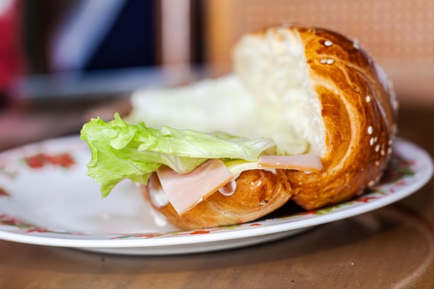 Photo sandwich avec du pain ouvert avec du fromage, du jambon, de la laitue et de la mayonnaise sur une assiette sur une table pour le petit déjeuner