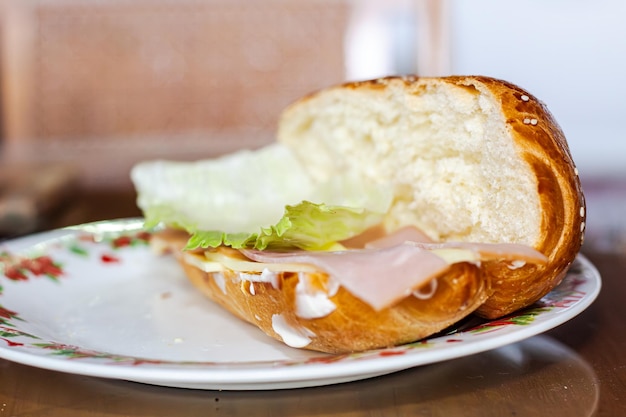 Photo sandwich avec du pain ouvert avec du fromage, du jambon, de la laitue et de la mayonnaise sur une assiette sur une table pour le petit déjeuner