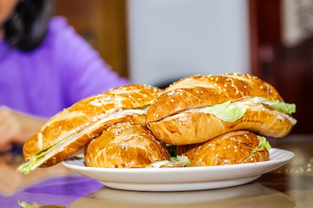 Photo sandwich avec du pain ouvert avec du fromage, du jambon, de la laitue et de la mayonnaise sur une assiette sur une table pour le petit déjeuner