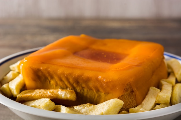 Sandwich francesinha portugais typique avec frites sur table en bois