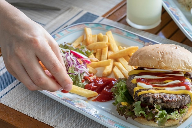 Sandwich avec galette de hamburger sur la table part trempant des frites dans du ketchup délicieux fas lumineux