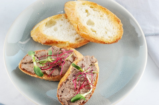 Sandwich grillé avec du pâté et des herbes sur une assiette bleue