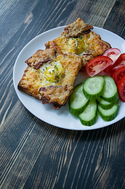 Sandwich grillé avec oeuf, légumes et bacon sur un fond en bois foncé