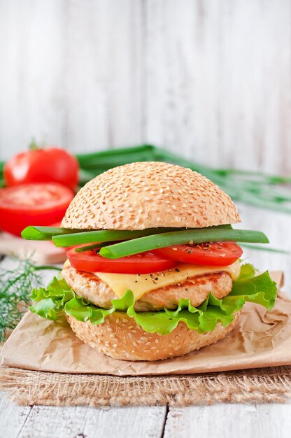 Sandwich avec hamburger au poulet, tomates, fromage et laitue.