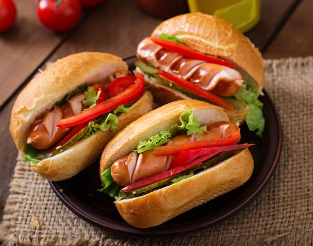 Sandwich à hot-dog avec des cornichons, du paprika et de la laitue sur fond de bois