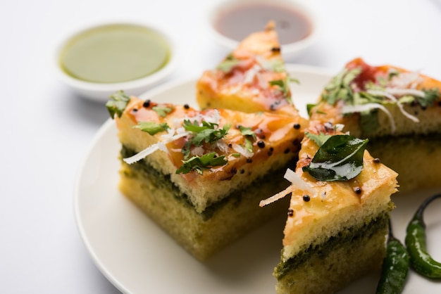 Le sandwich jaune Dhokla est un en-cas salé indien à base de farine de pois chiches ou de farine de riz, originaire du Gujarat. Servi avec chutney vert et tamarin. mise au point sélective