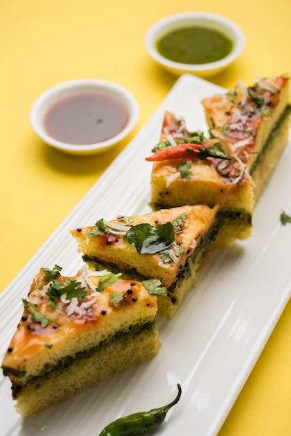 Le sandwich jaune Dhokla est un en-cas salé indien à base de farine de pois chiches ou de farine de riz, originaire du Gujarat. Servi avec chutney vert et tamarin. mise au point sélective