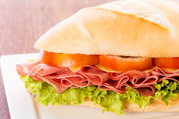 Sandwich à la mortadelle, sur une table en bois.