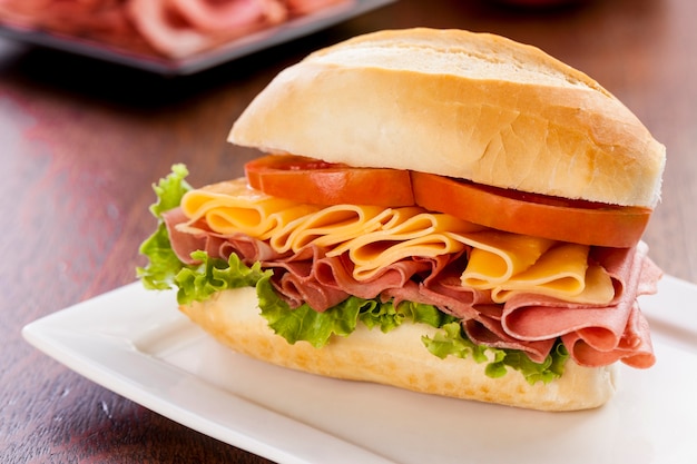 Sandwich à la mortadelle, sur une table en bois.