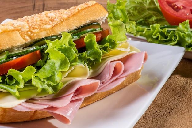Sandwich naturel sur pain baguette avec fromage, jambon et garniture de salade.