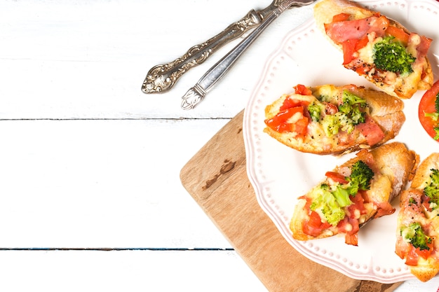 Sandwich ouvert avec prosciutto, mozzarella et tomates sur table de cuisine, focus superficiel