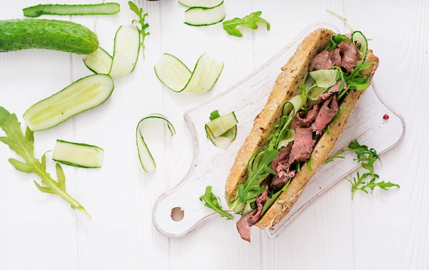 Sandwich de pain de blé entier avec rôti de boeuf, de concombre et de roquette. Vue de dessus Plat poser.