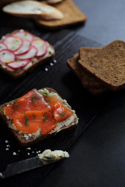 Sandwich avec pain de céréales saumon fumé betterave et concombre sur fond de marbre foncé