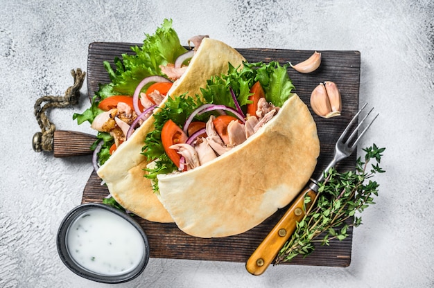 Sandwich pita avec poulet rôti, légumes et sauce délicieuse. Fond blanc. Vue de dessus.