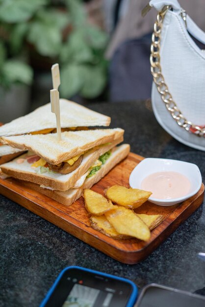 Photo un sandwich sur une planche à couper avec des chips et un bol de trempette