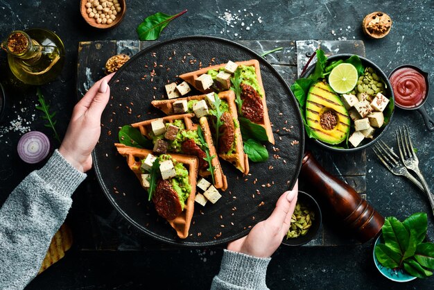 Sandwich pour le petit déjeuner gaufres belges avec pate d'avocat tomates séchées et tofu fromage Le concept de nutrition diététique Sur un fond de pierre