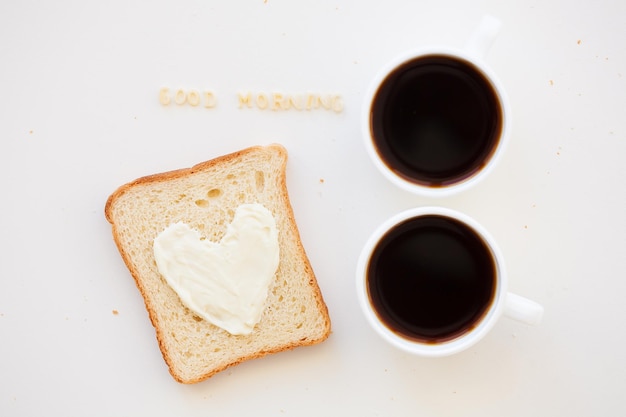 Sandwich pour le petit déjeuner sous forme de coeur avec du fromage - bon signe du matin et deux tasses à café