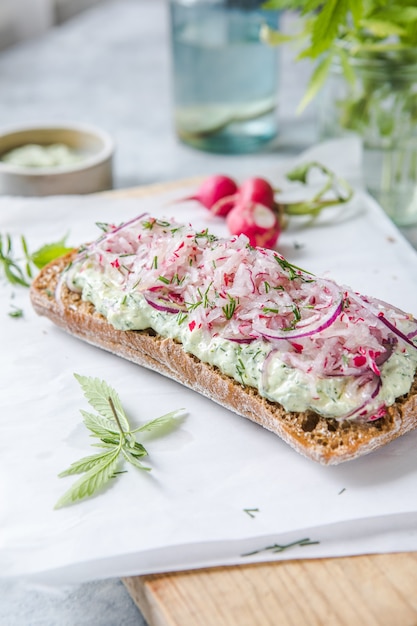 Sandwich de printemps vert frais avec fromage à la crème et radis sur fond clair. Espace de copie