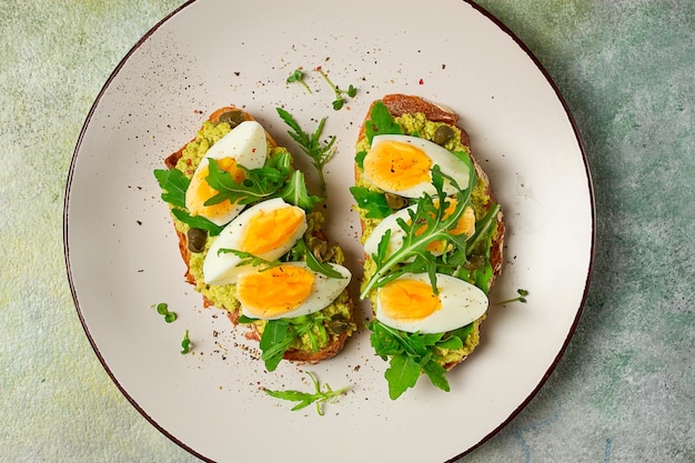 sandwich avec purée d'avocat œuf bouilli et roguela sur pain petit déjeuner fait maison