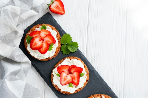 Photo sandwich sain avec fraise et fromage à la crème sur ardoise petit-déjeuner savoureux régime alimentaire propre ou recette facile de sandwich végétarien pour menu végétalien mise à plat