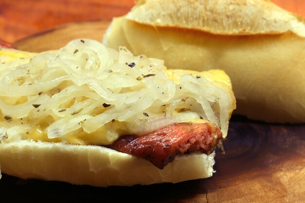 Photo sandwich à la saucisse calabraise choripan avec du fromage et de l'oignon sur un fond de bois