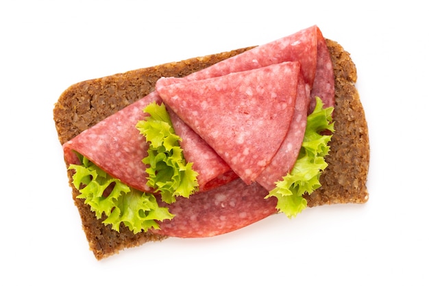 Sandwich avec saucisse salami sur table blanche.