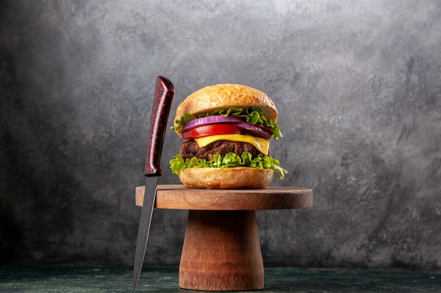 Sandwich savoureux et fourchette rouge sur une planche à découper en bois sur une surface de couleur sombre avec un espace libre