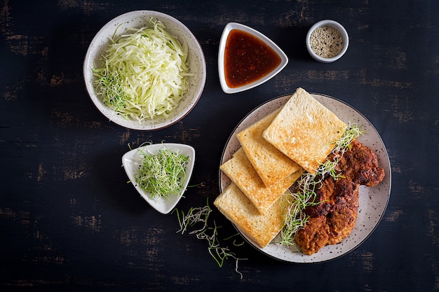 Photo sandwich tendance japonaise avec côtelette de porc panée, sauce chou et tonkatsu.