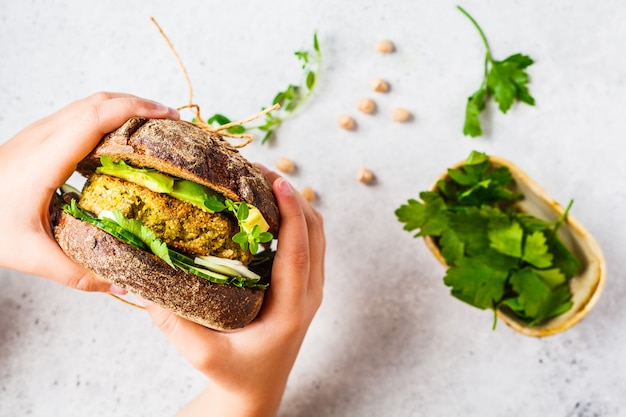 Sandwich végétalien avec galette de pois chiches, avocat, concombre et légumes verts en pain de seigle