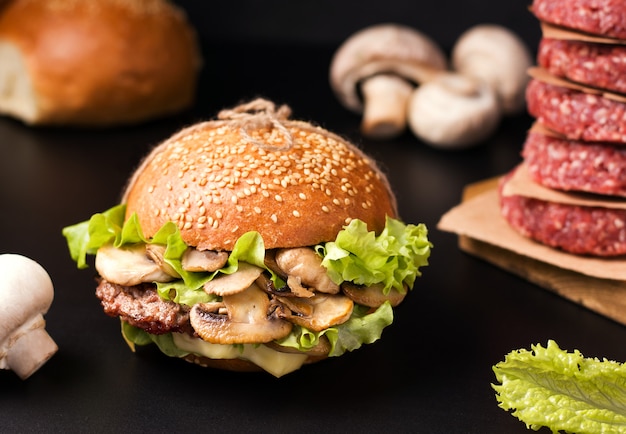 Sandwich à la viande et aux champignons sur une planche de bois à côté des ingrédients