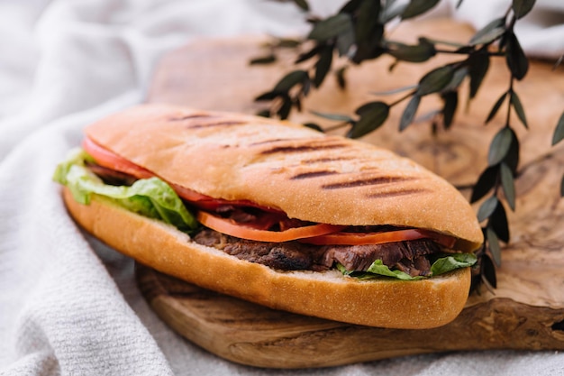 Sandwich avec de la viande et des légumes sur une planche de bois