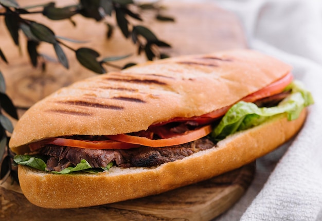 Sandwich avec de la viande et des légumes sur une planche de bois