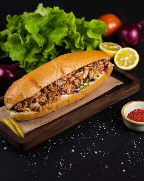 Photo un sandwich avec de la viande et des légumes sur une planche de bois.