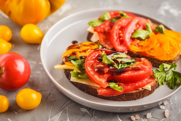 Sandwiches aux tomates et fromage sur assiette grise, vue de dessus.