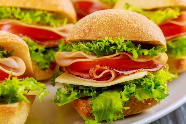 Sandwiches colorés sur plaque blanche sur table en bois