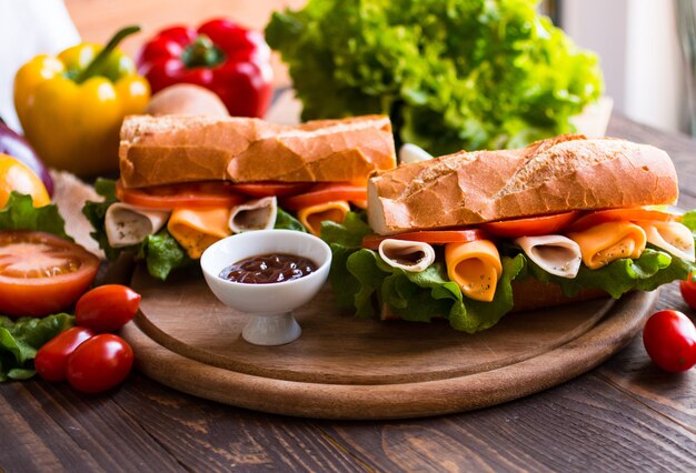 Sandwiches délicieux avec de la dinde, du jambon, du fromage et des tomates