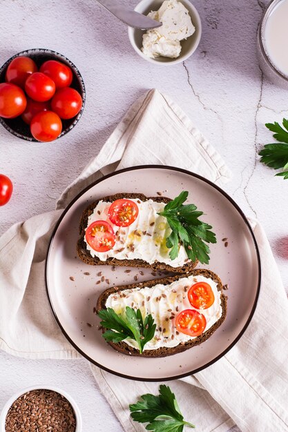 Sandwiches sur pain de seigle avec tomates ricotta et persil sur une assiette Vue de dessus et verticale