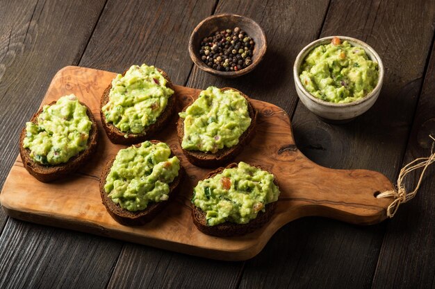 Sandwiches à la sauce guacamole sur une planche à découper sur fond de bois ancien