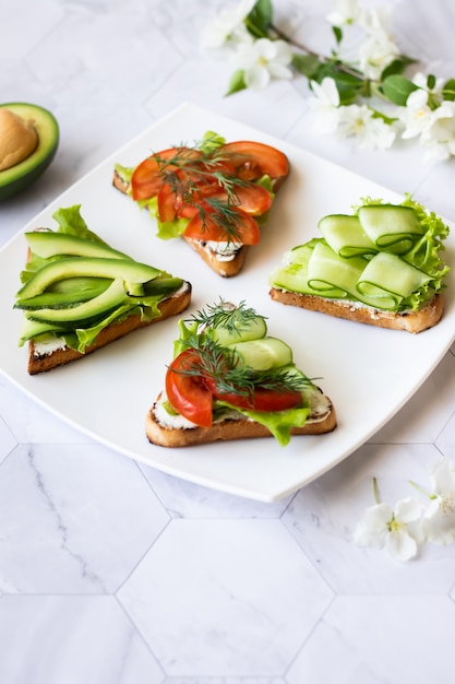 Sandwiches végétariens à l'avocat, tomates et concombres sur un fond clair