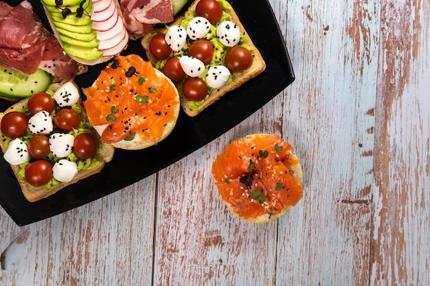 Sandwichs assortis avec du poisson, du fromage, de la viande et des légumes sur une plaque noire