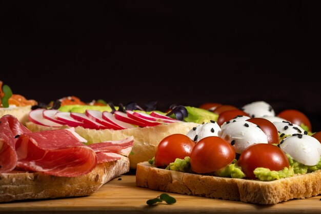 Sandwichs assortis avec du poisson, du fromage, de la viande et des légumes se trouvant sur la planche