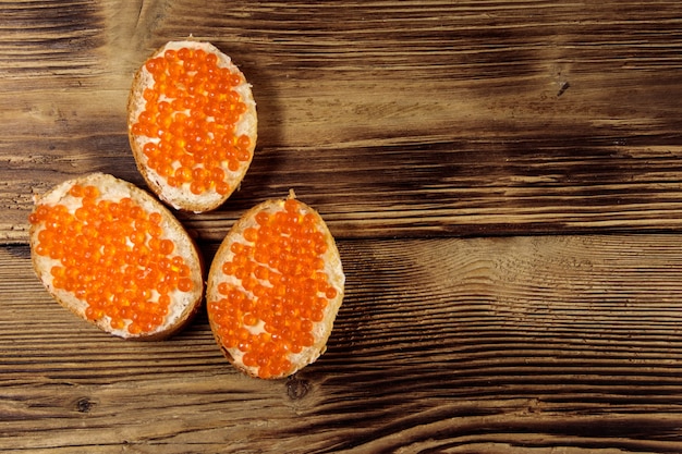 Sandwichs au beurre et caviar rouge sur table en bois