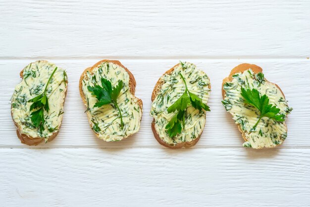 Sandwichs au beurre d'herbes sur fond de bois blanc.