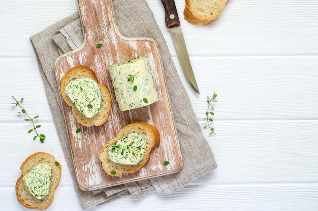 Sandwichs au beurre d'herbes sur une planche à découper sur fond de bois blanc.